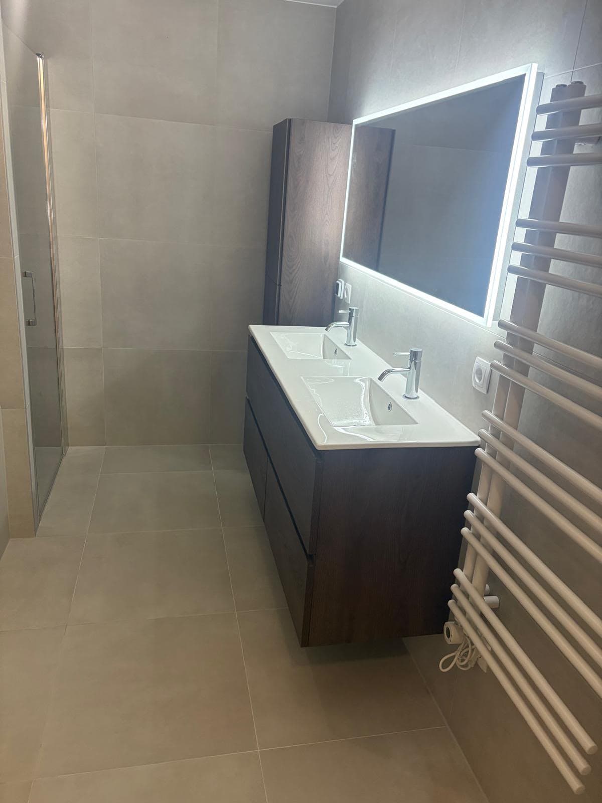 Bathroom with floating vanity unit, illuminated mirror and large wall and floor tiles