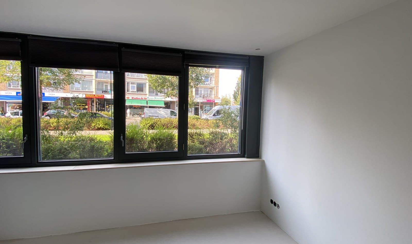 Kamer met strak afgewerkte witte wanden en plafond en een brede raampartij